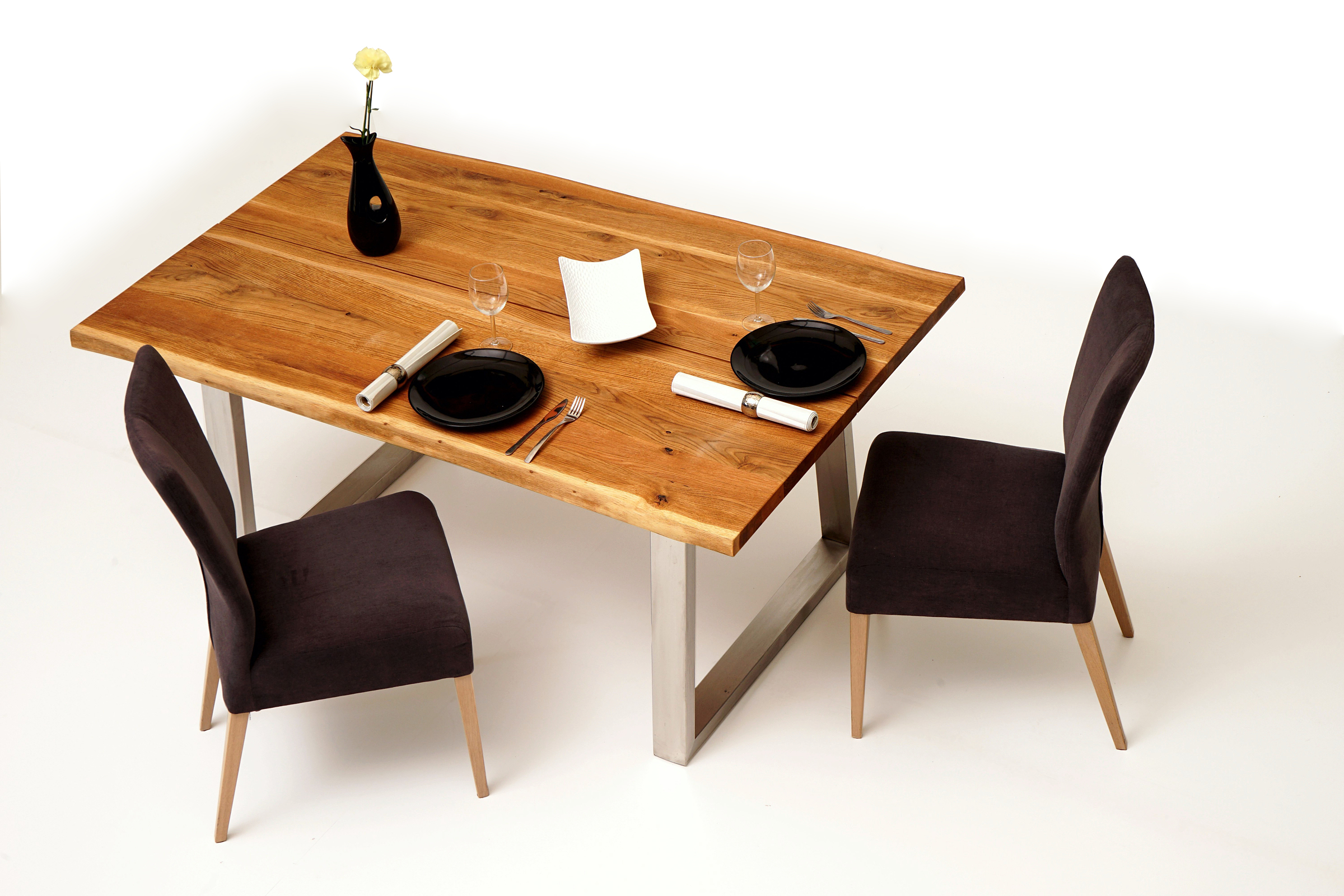 Roums pomysł aranżacja nowoczesnego salonu z meblami metalowymi - dębowy stół loftowy z nogami ze stali szczotkowanej, czarne talerze i wazon, biały półmisek na owoce patera, ciemno brązowe krzesła tapicerowane tkaniną z drewnianymi nogami