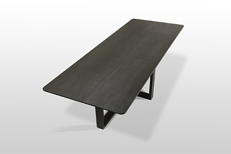 Stół z ciemny spiekowym blatem firmy Laminam, posiada zaokrąglone rogi oraz chropowatą powierzchnię. Meble z Dobrodzienia
