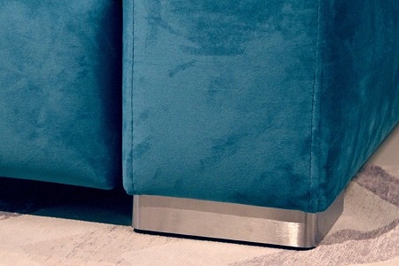 Livio - detal nogi metalowej ze stali szczotkowanej w narożniku tapicerowanym tkaniną w kolorze turkusowym