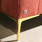 Złota nóżka w nowoczesnej sofie tapicerowanej tkaniną w kolorze czerwonym