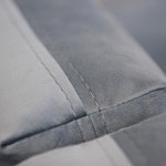 Detal szycia poduszek oparcia szarego narożnika tapicerowanego tkaniną welurową