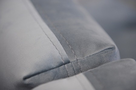 Detal szycia poduszek oparcia szarego narożnika tapicerowanego tkaniną welurową